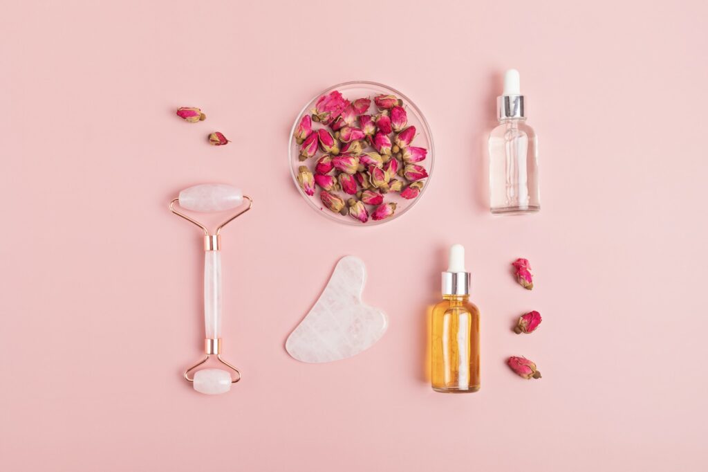 Rose quartz face roller, gua sha stone, essential oil and dry roses